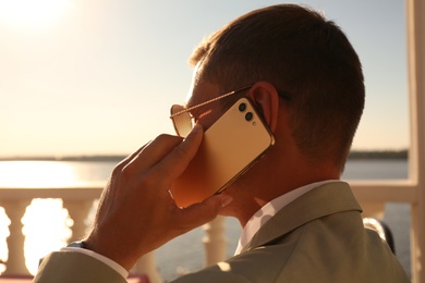 Photo of Businessman talking on smartphone in outdoor cafe