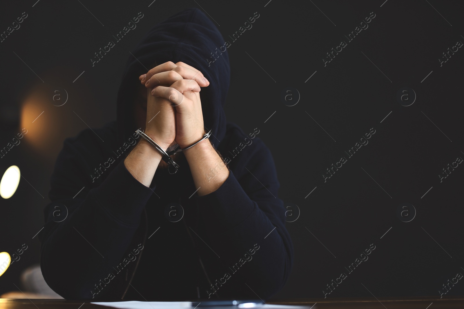 Photo of Criminal in handcuffs with confession at desk indoors. Space for text