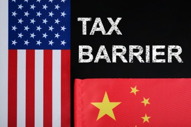 Photo of Phrase TAX BARRIER, USA and China flags on black background, flat lay