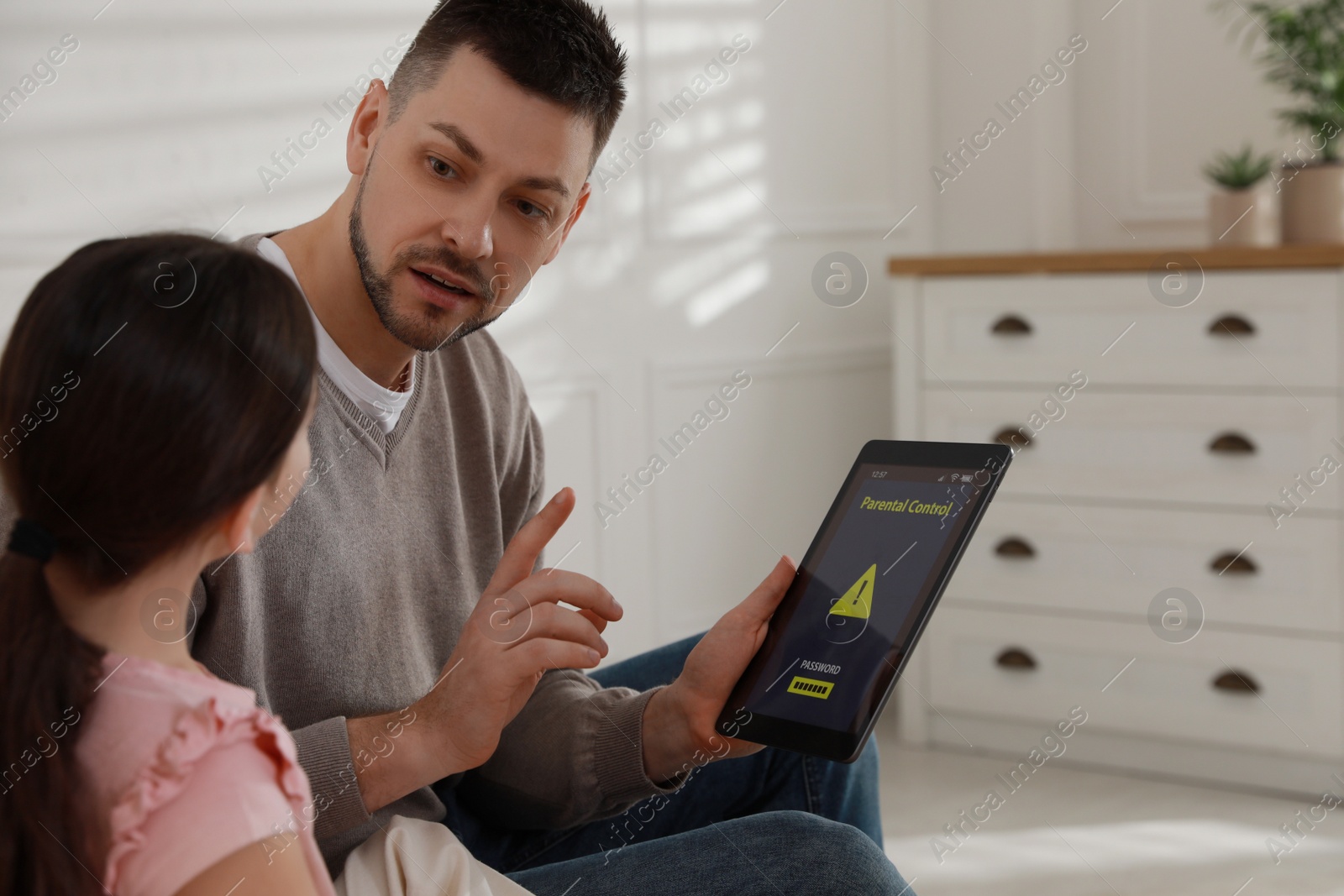 Photo of Dad installing parental control on tablet at home. Child safety