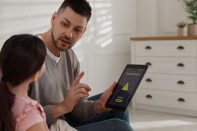 Photo of Dad installing parental control on tablet at home. Child safety