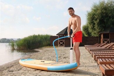 Man pumping up SUP board on river shore