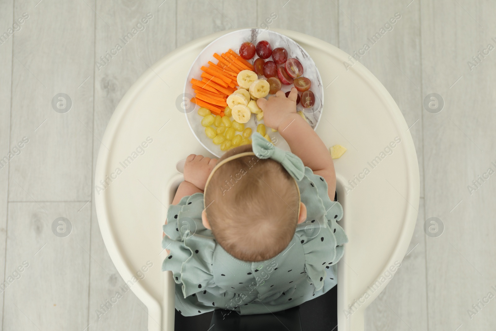 Photo of Cute little girl eating healthy food, top view