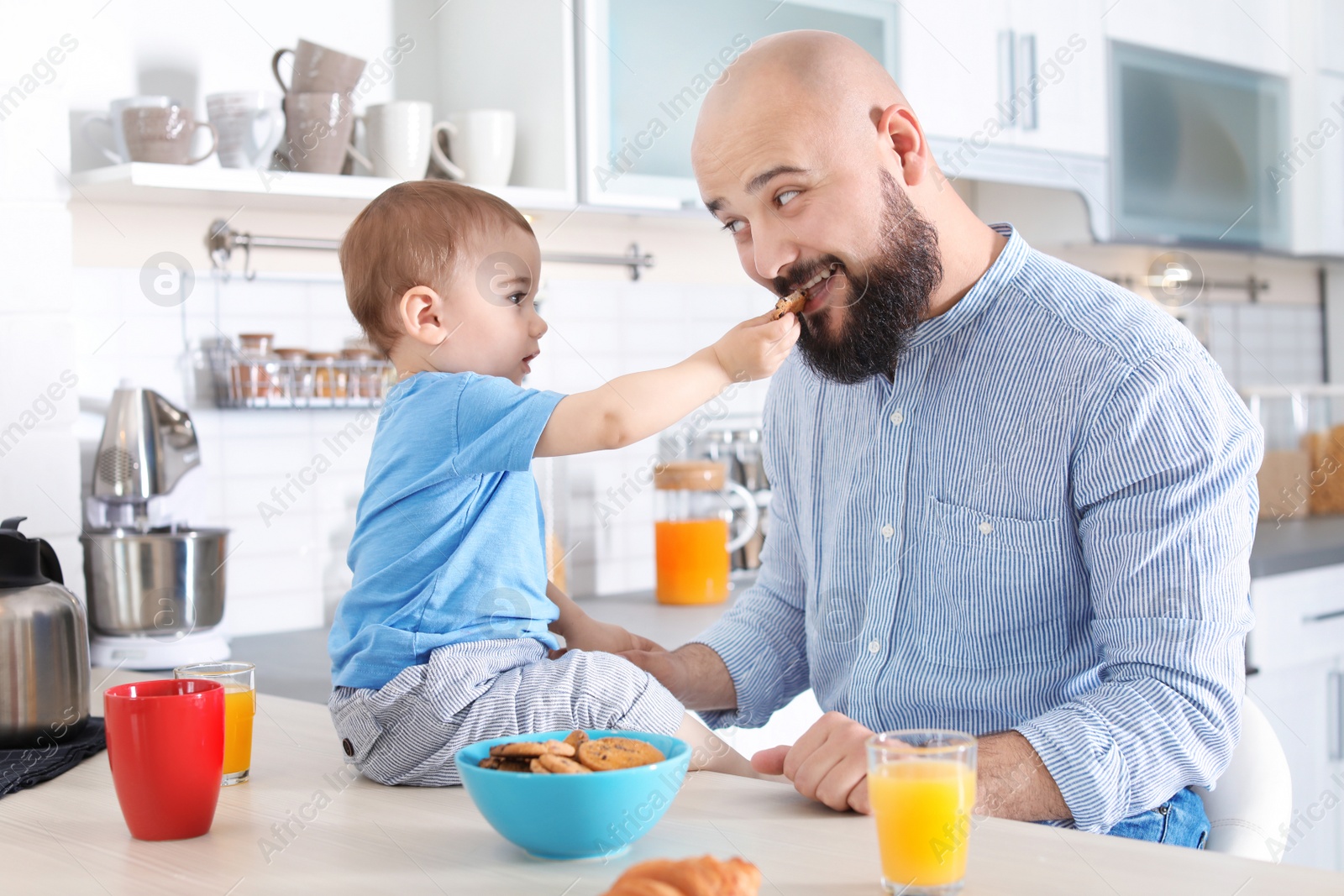 Photo of Dad having breakfast with little son in kitchen