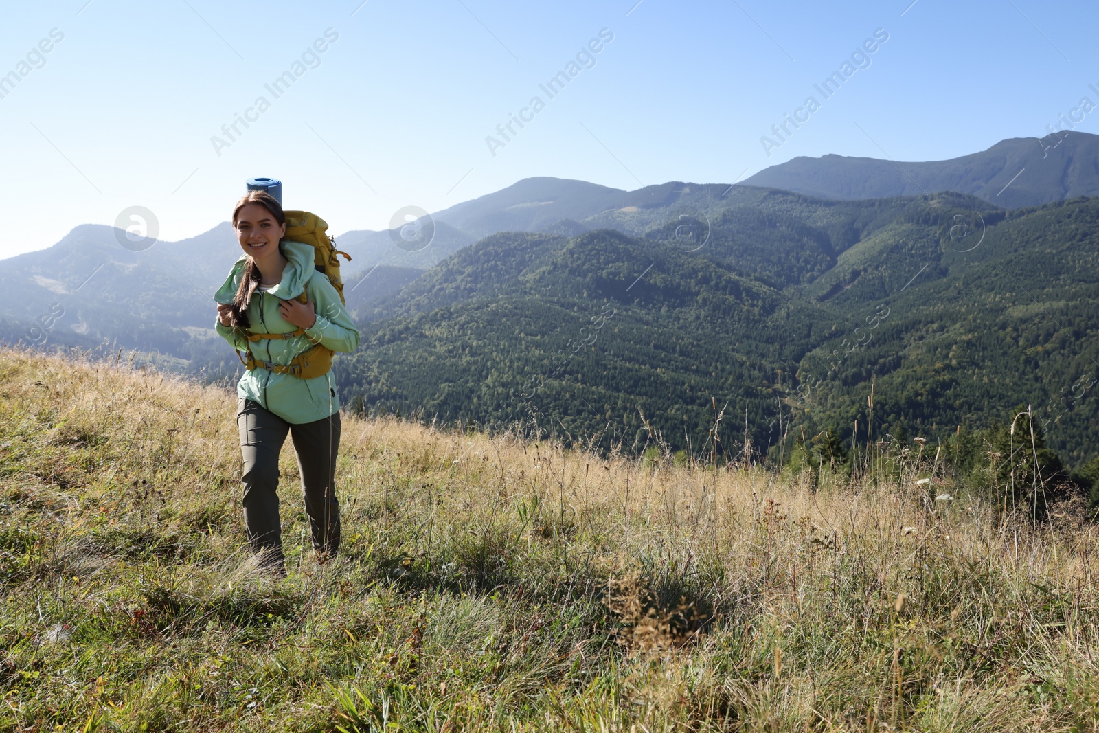 Photo of Tourist with backpack walking in mountains on sunny day