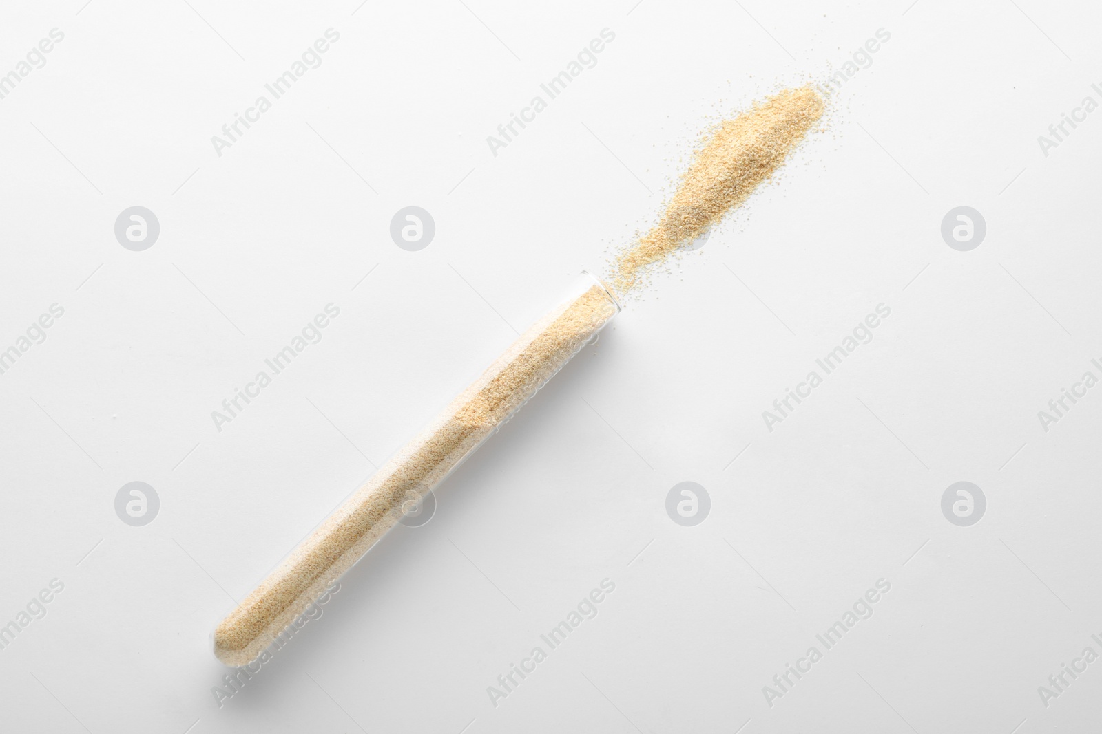 Photo of Glass tube with garlic powder on white background, top view