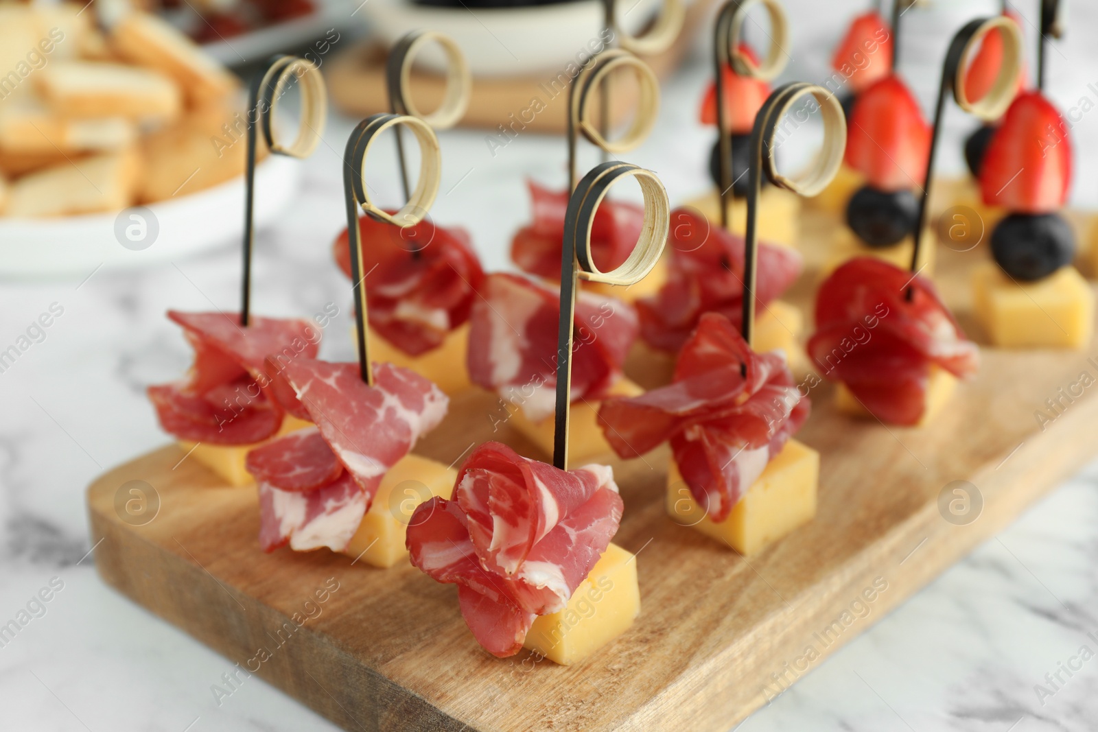 Photo of Different tasty canapes on white marble table, closeup