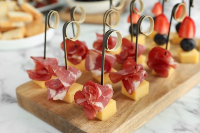 Photo of Different tasty canapes on white marble table, closeup