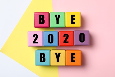 Cubes with phrase Bye 2020 Bye on color background, flat lay