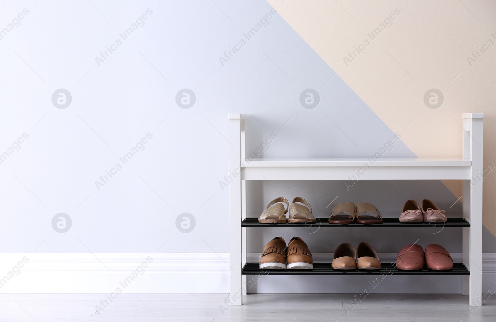 Photo of Shoe rack with different footwear near color wall, space for text. Stylish hallway interior