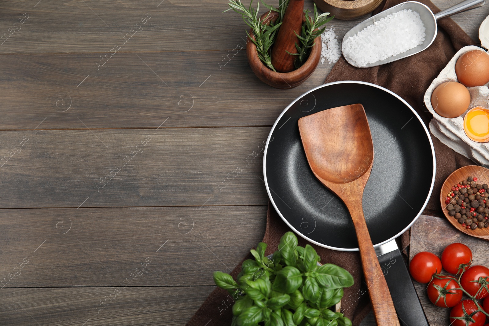 Photo of Flat lay composition with cooking utensils, frying pan and fresh ingredients on wooden table. Space for text