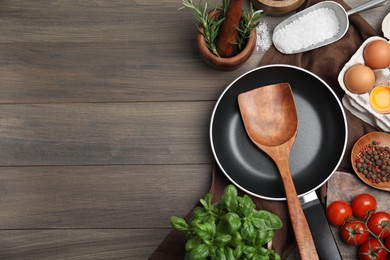 Photo of Flat lay composition with cooking utensils, frying pan and fresh ingredients on wooden table. Space for text