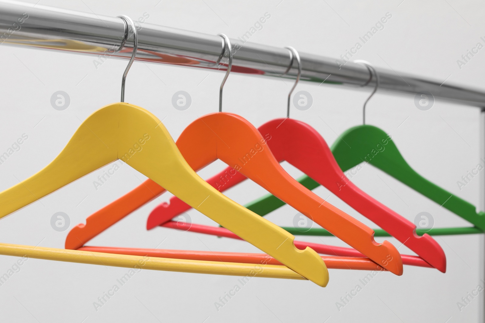 Photo of Clothes hangers on metal rail against light background