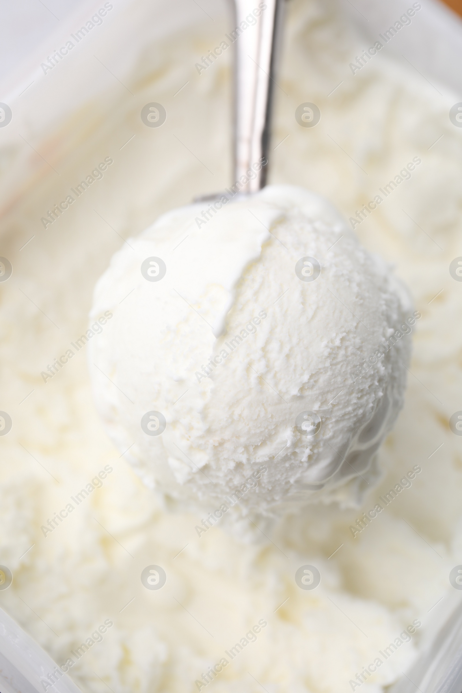 Photo of Steel scoop with tasty vanilla ice cream, closeup