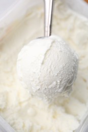Photo of Steel scoop with tasty vanilla ice cream, closeup