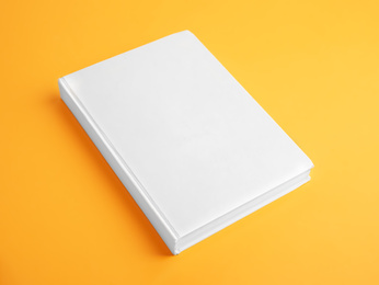 Book with blank cover on yellow background