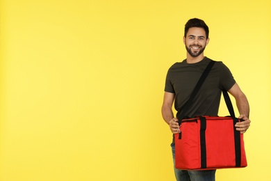 Young courier with thermo bag on color background, space for text. Food delivery service