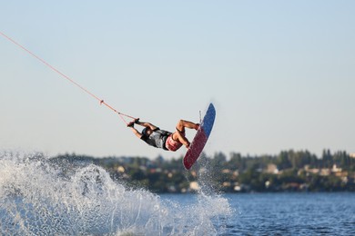 Photo of Teenage wakeboarder doing trick over river. Extreme water sport