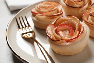 Photo of Freshly baked apple roses served on light table, closeup. Beautiful dessert
