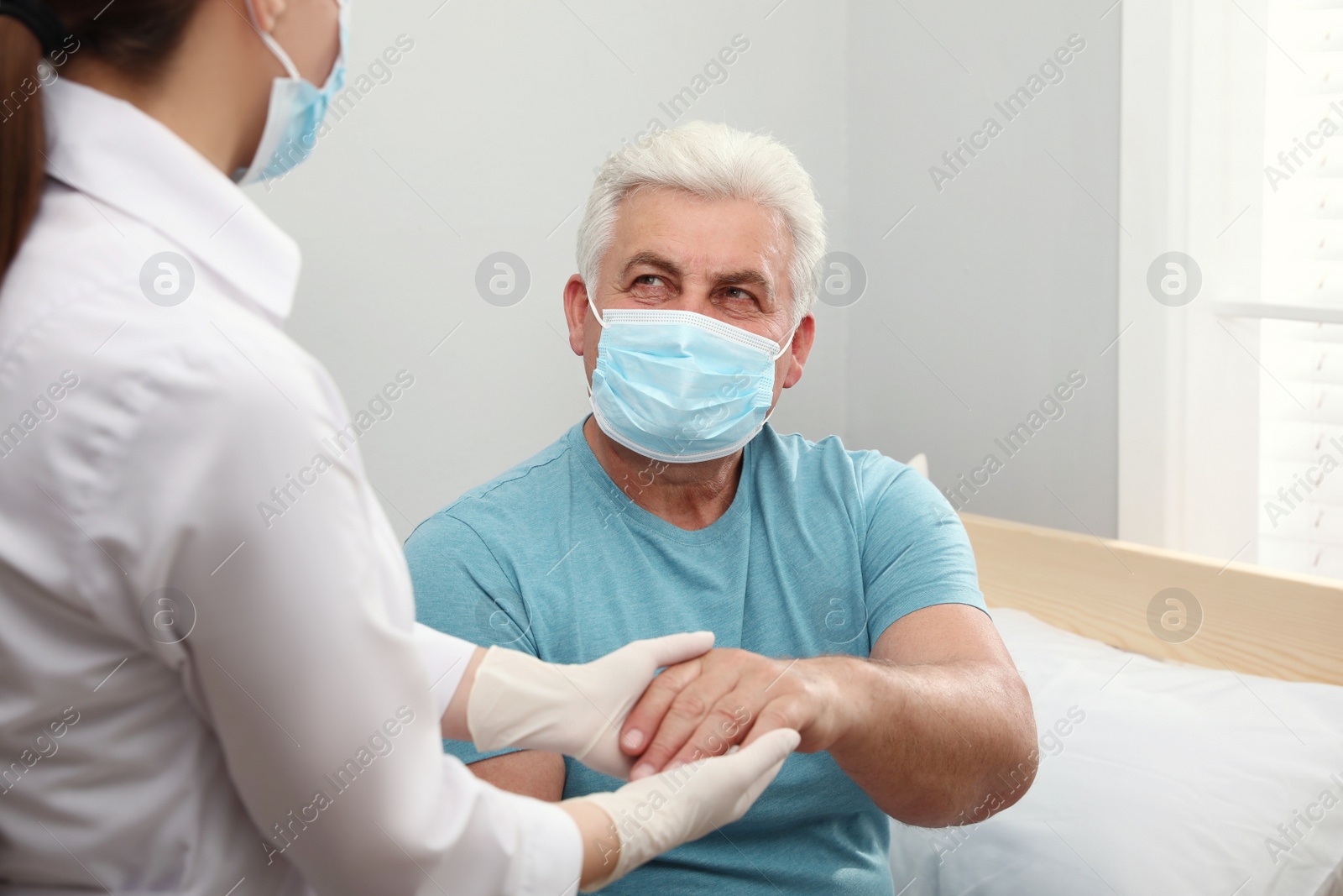 Photo of Doctor taking care of senior man with protective mask at nursing home