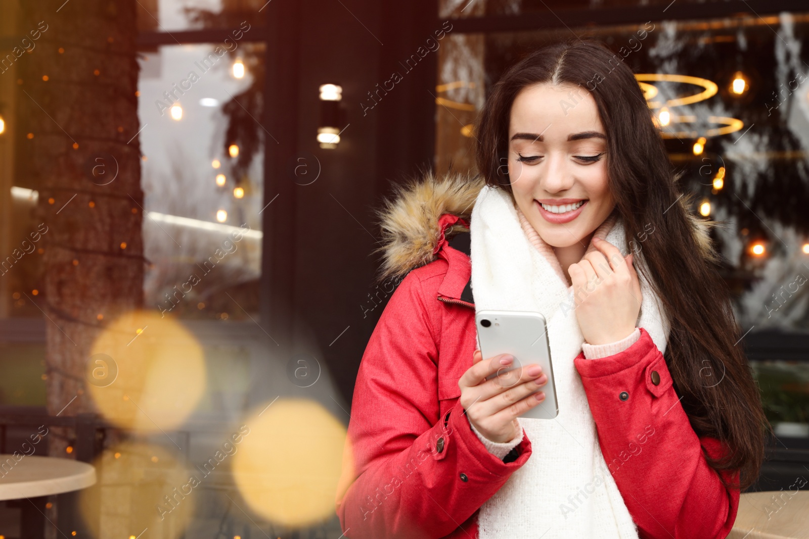 Photo of Young woman with smartphone at winter fair. Christmas celebration