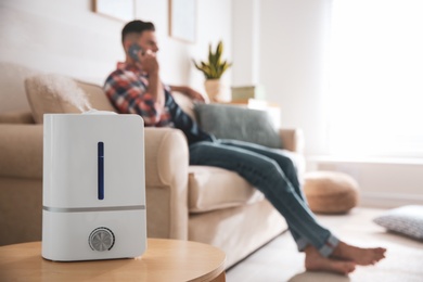 Modern air humidifier and blurred man on background