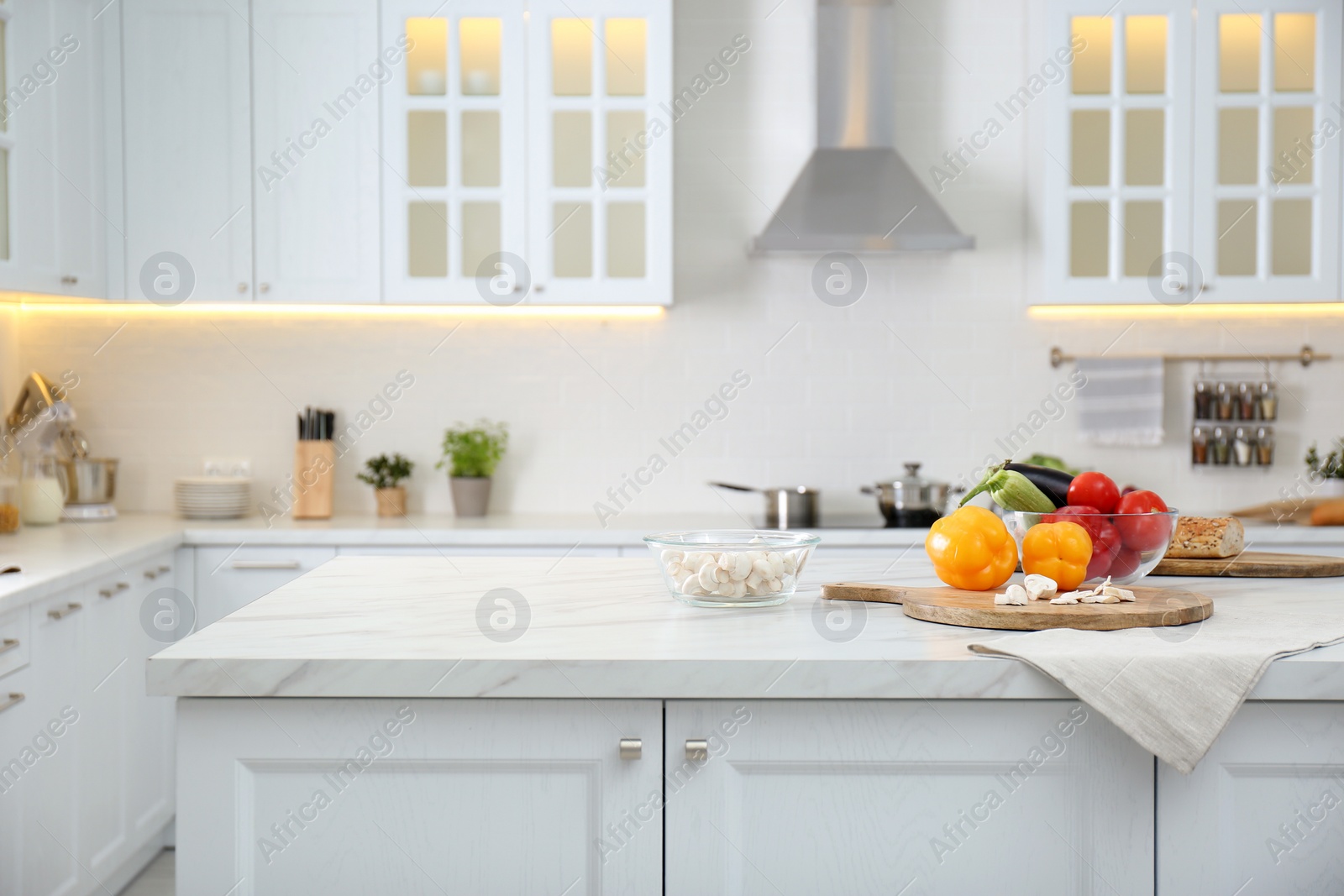 Photo of Different fresh vegetables and mushrooms on white table in modern kitchen. Space for text