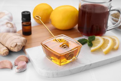 Photo of Cold remedies. Bowl of honey, ginger, lemon and syrup on white table. Cough treatment