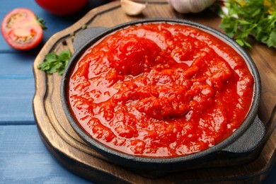 Photo of Homemade tomato sauce in bowl on blue wooden table, closeup