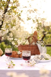 Photo of Stylish table setting with beautiful spring flowers, wine and croissants in garden