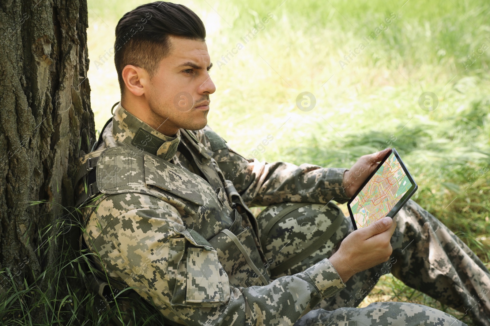 Photo of Soldier using tablet near tree in forest