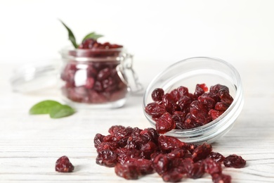 Photo of Tasty dried cranberries on white wooden table. Space for text