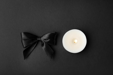 Ribbon and candle on black background, top view. Funeral symbols