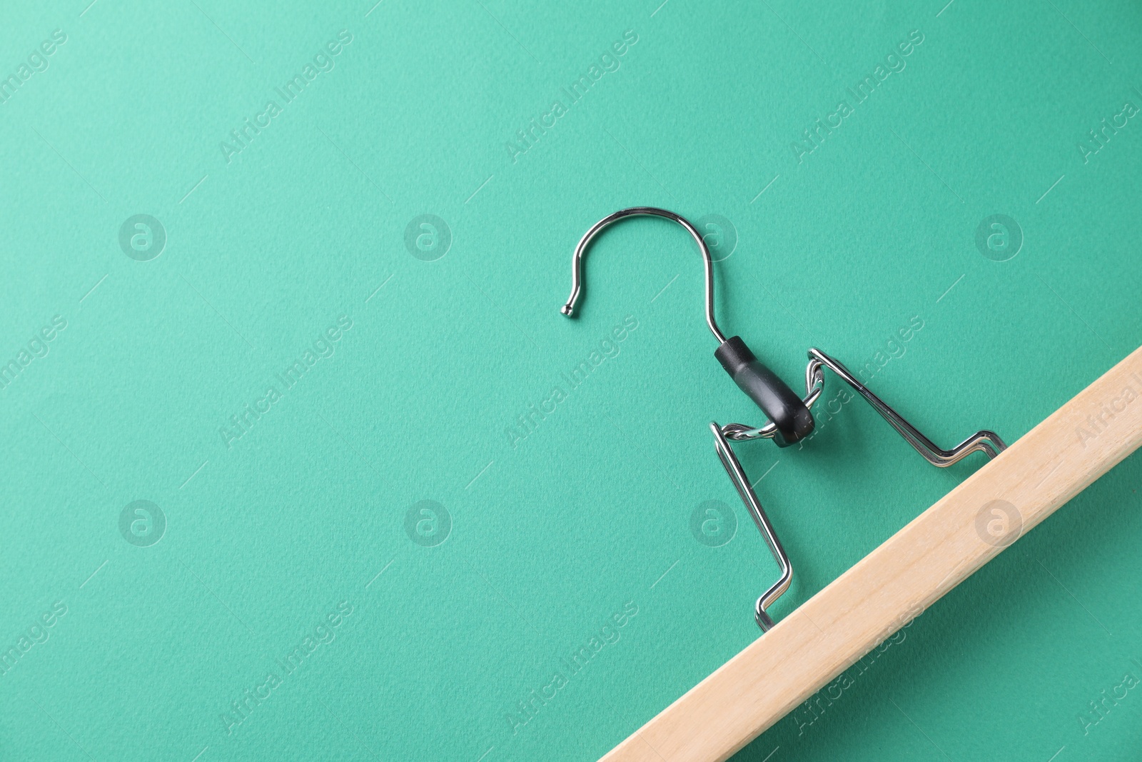 Photo of One wooden hanger on dark turquoise background, top view. Space for text