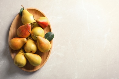 Photo of Plate with ripe pears on light background, top view. Space for text