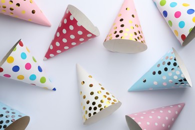 Colorful party hats on light background, top view