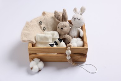 Different baby accessories and clothes in wooden crate on white background
