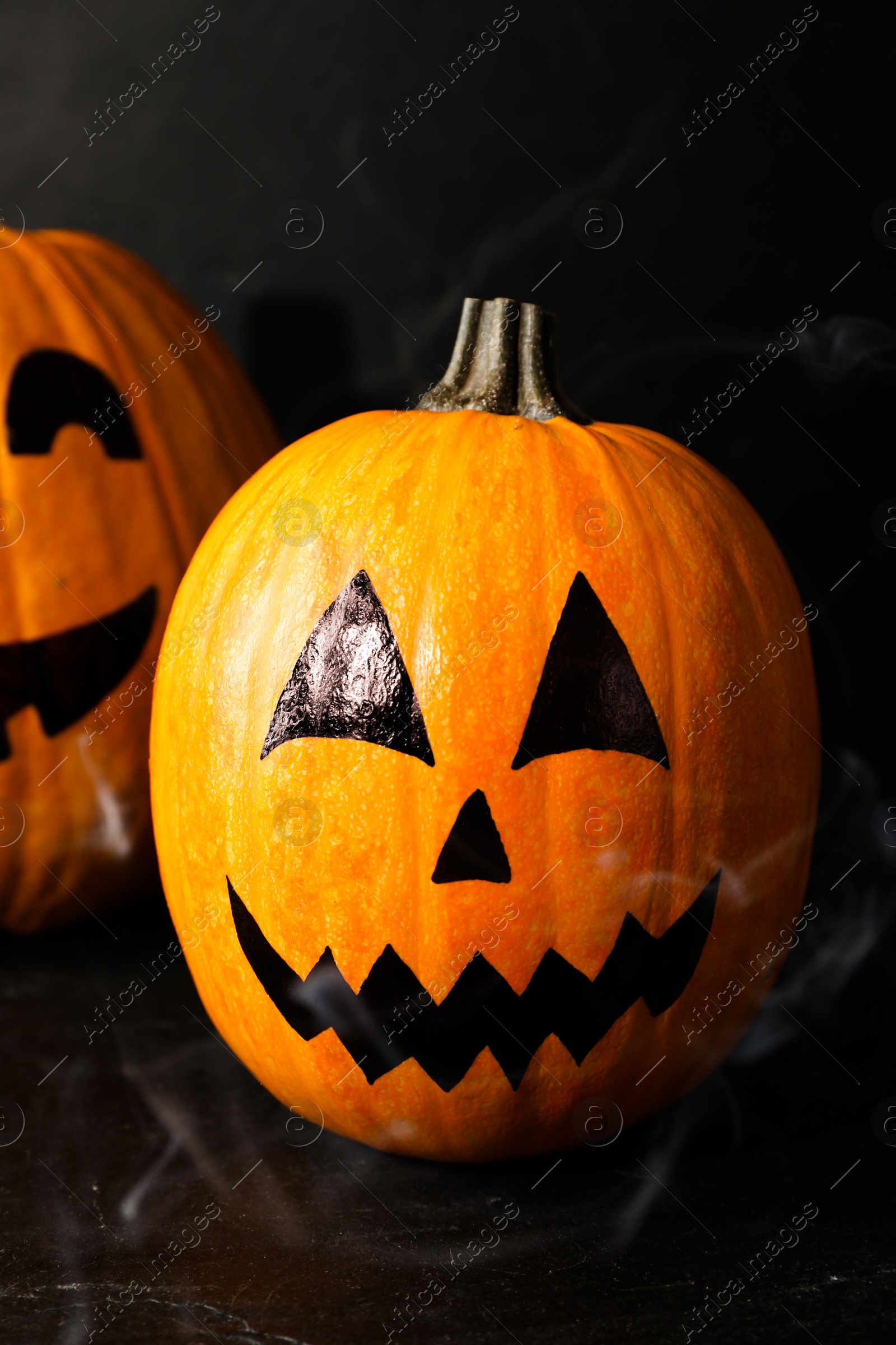 Photo of Pumpkins with drawn spooky faces on dark background. Halloween celebration