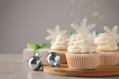 Photo of Tasty Christmas cupcakes with snowflakes on grey table. Space for text