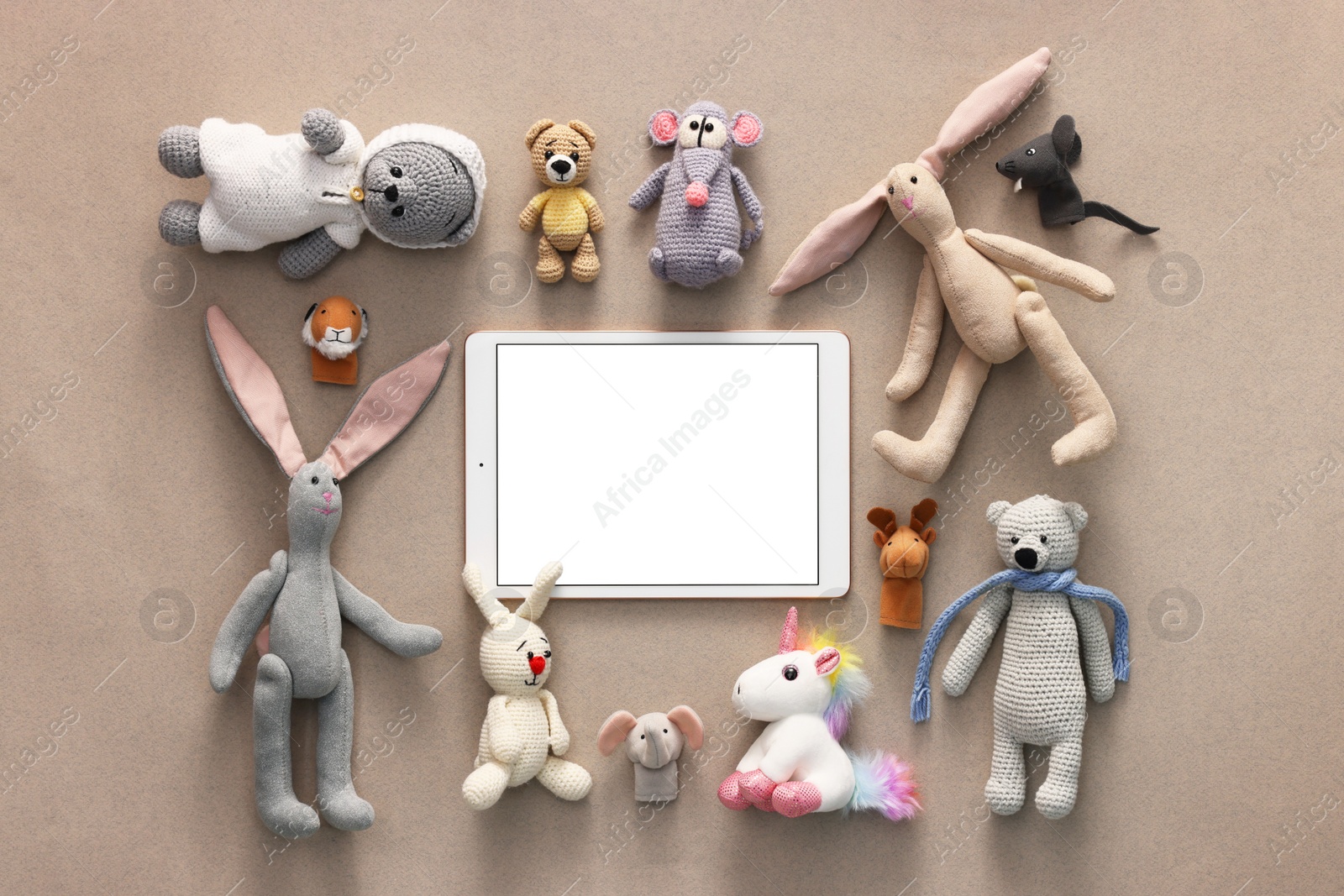 Photo of Modern tablet and kid's toys on light brown background, flat lay. Space for text