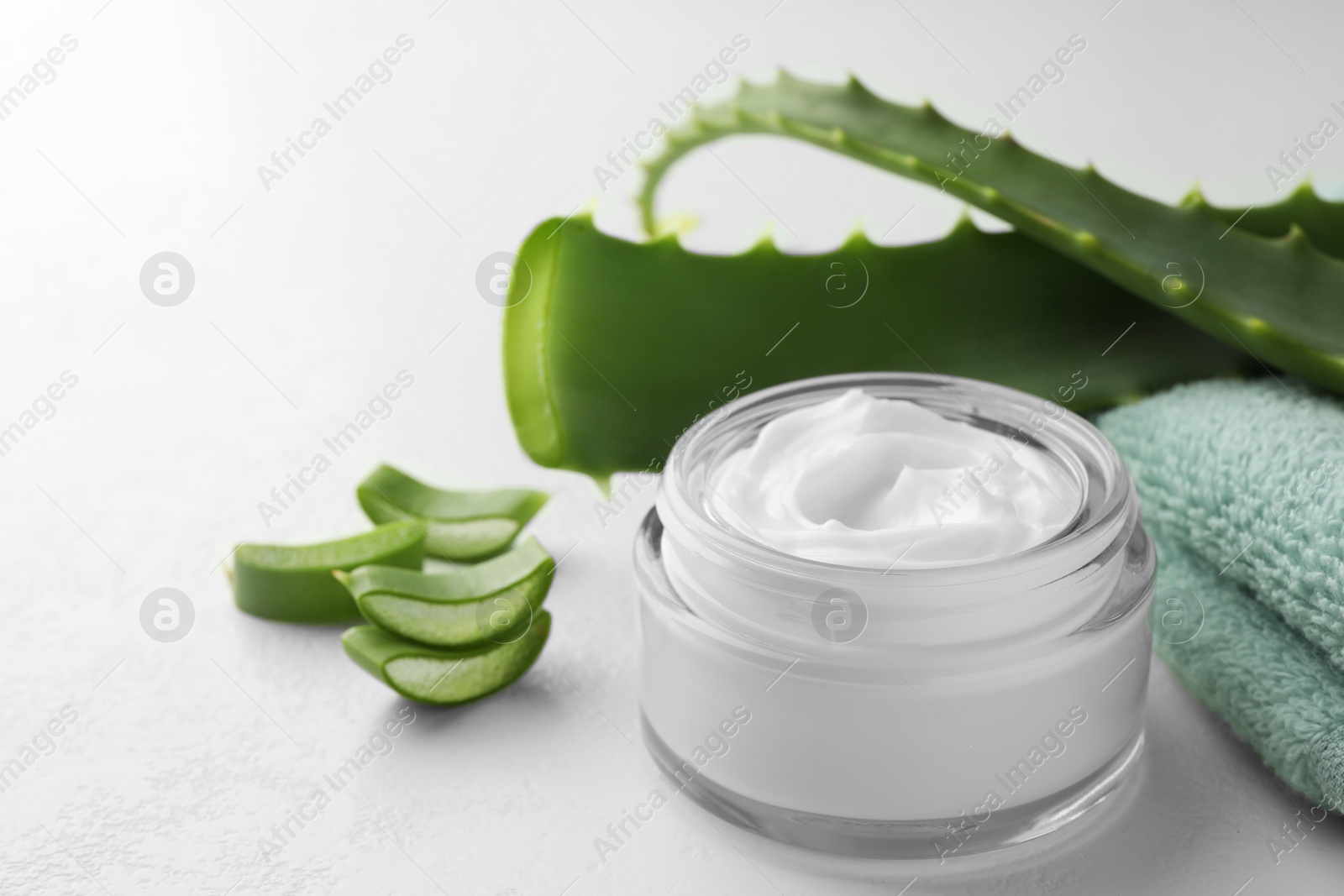 Photo of Jar with cream and cut aloe leaves on white table, closeup. Space for text