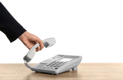 Young woman picking up telephone on white background