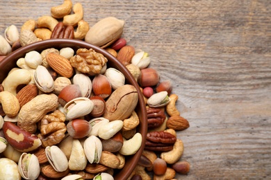 Flat lay composition with mixed organic nuts and space for text on wooden background, top view