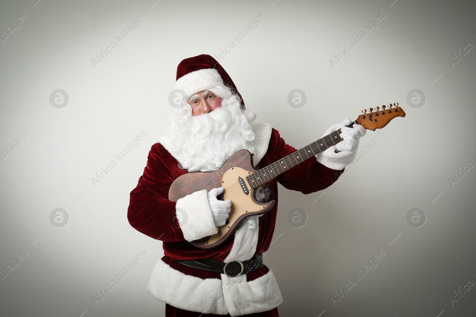 Photo of Santa Claus playing electric guitar on light background. Christmas music