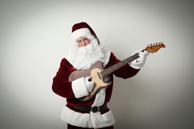 Santa Claus playing electric guitar on light background. Christmas music