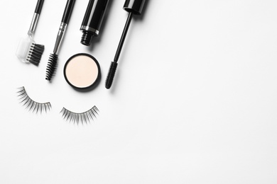 Photo of Composition with false eyelashes and other makeup products on white background, top view