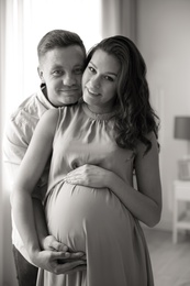 Pregnant woman with her husband indoors, black and white effect