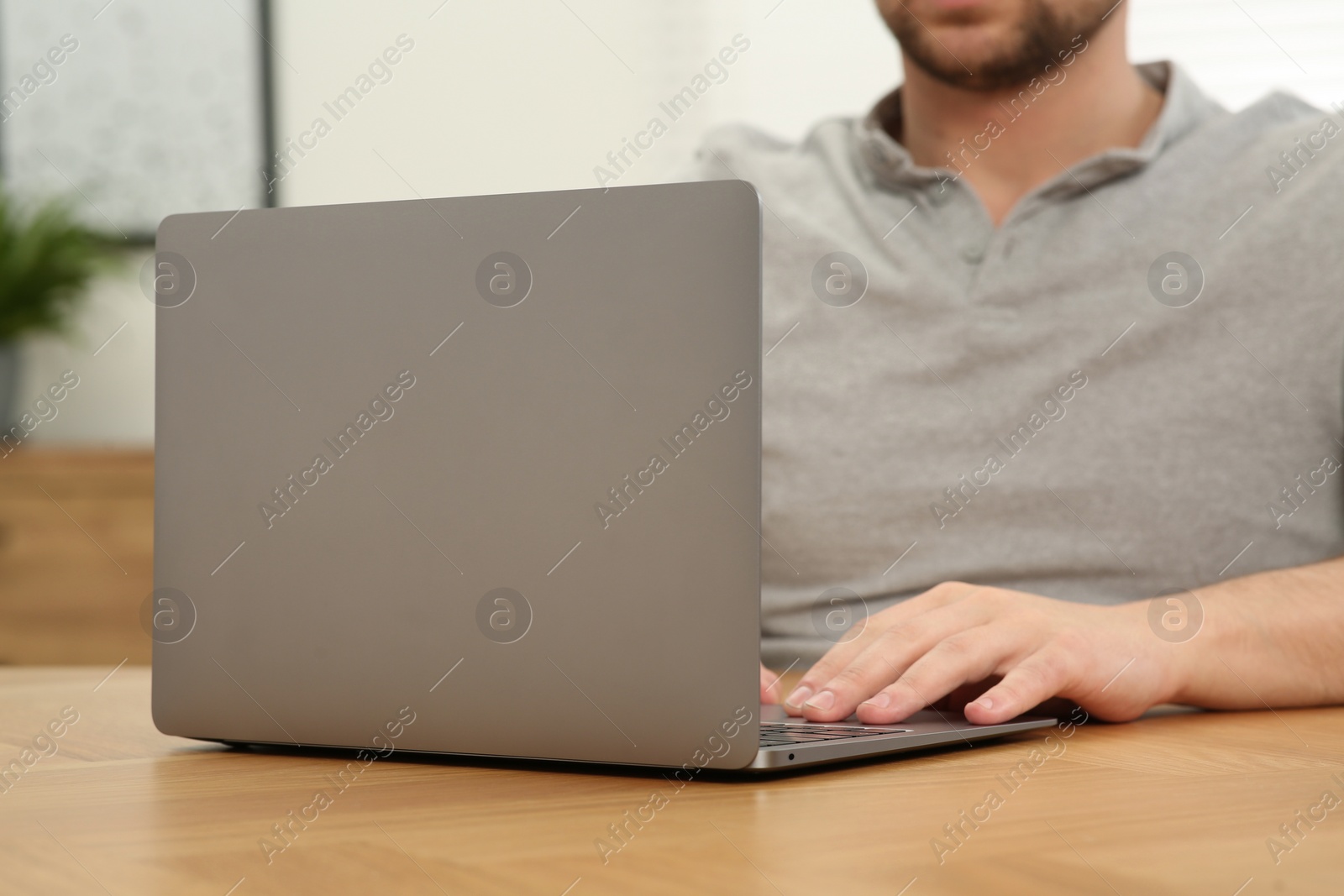 Photo of Man working with laptop at wooden table indoors, closeup