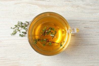 Photo of Cup of fresh thyme tea on wooden table, top view