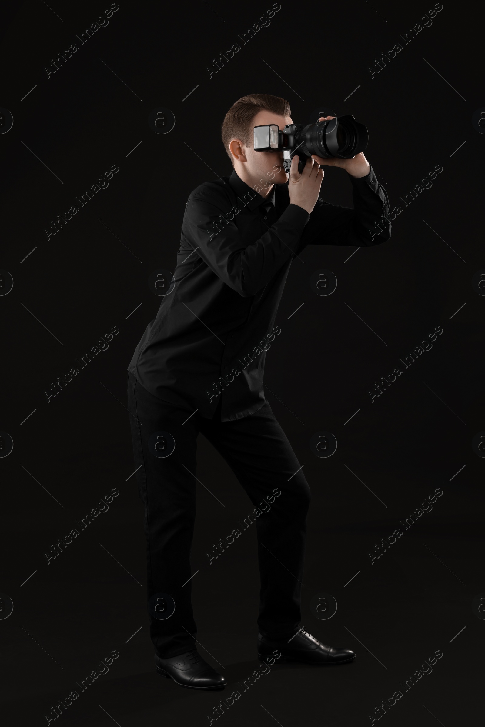 Photo of Professional photographer taking picture on black background